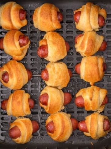 Close up of pigs in a blanket in the air fryer basket.