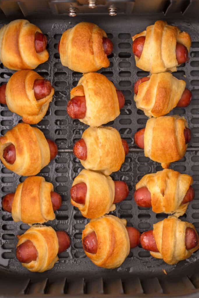 Close up of pigs in a blanket in the air fryer basket.