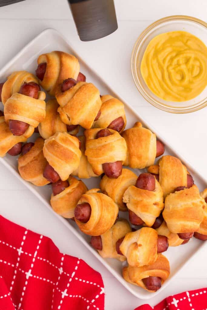 Air fryer pigs in a blanket on a white serving tray.