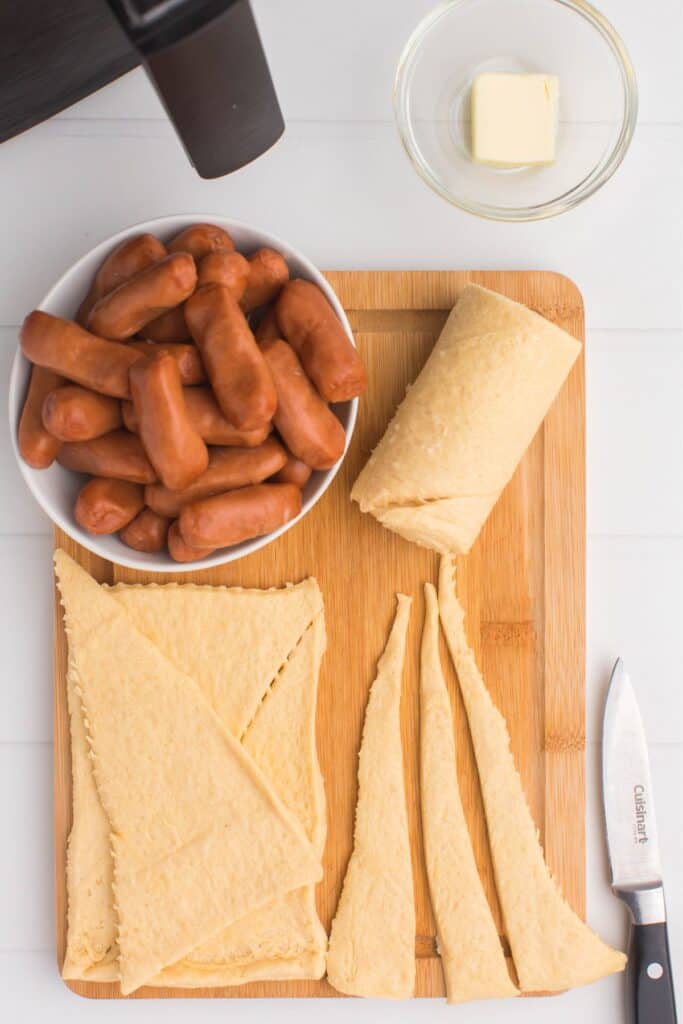 Ingredients needed to make air fryer pigs in a blanket: canned crescent rolls, lil smokies, and butter.