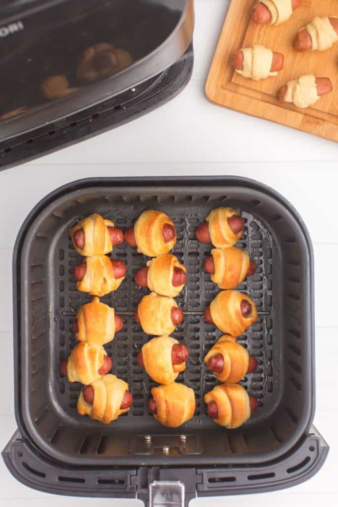 Cooked piggies in a blanket in an air fryer basket.