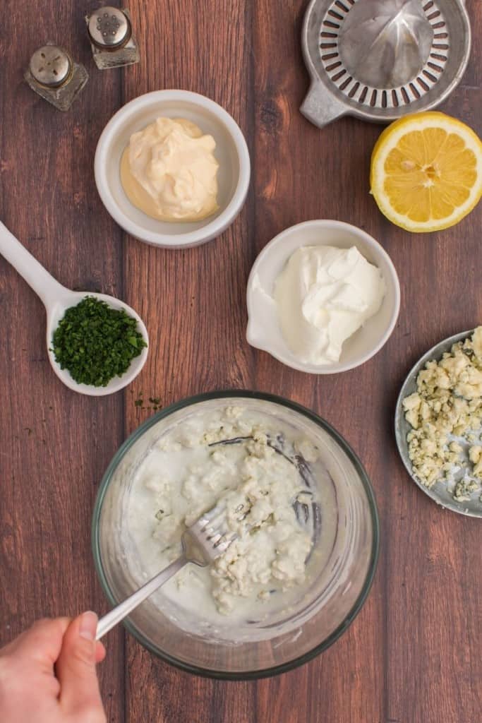 stirring ingredients in a bowl for blue cheese dressing