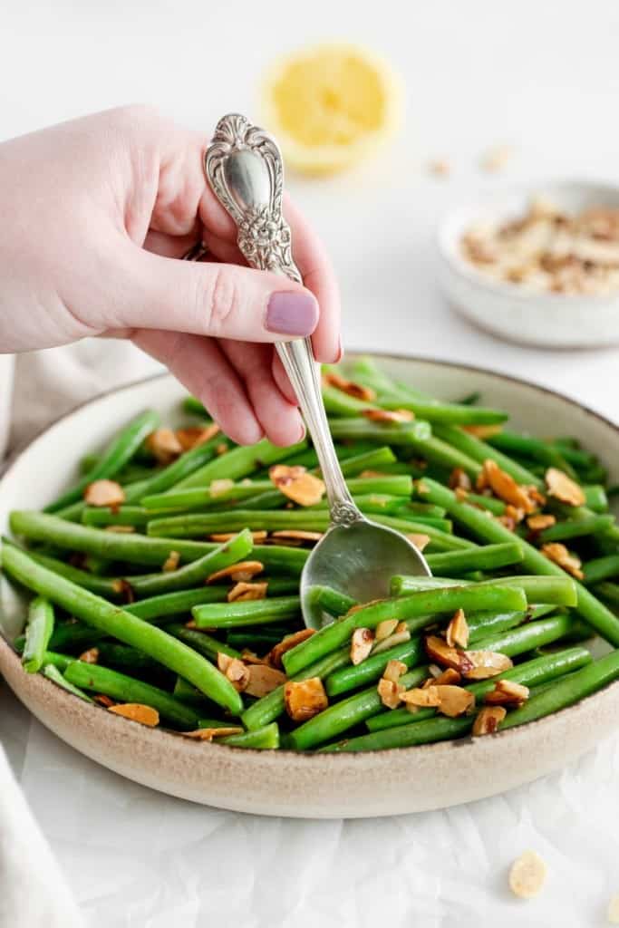 green beans almondine on a plate with a spoon