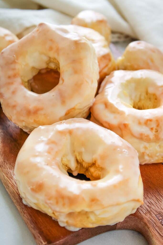 Air fryer donuts covered in glaze on a wooden serving board.