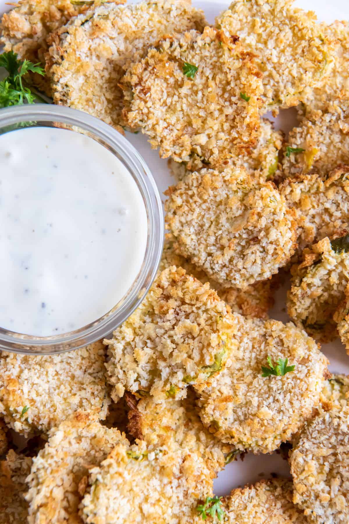 Air fryer fried pickles on a plate with a dipping sauce.