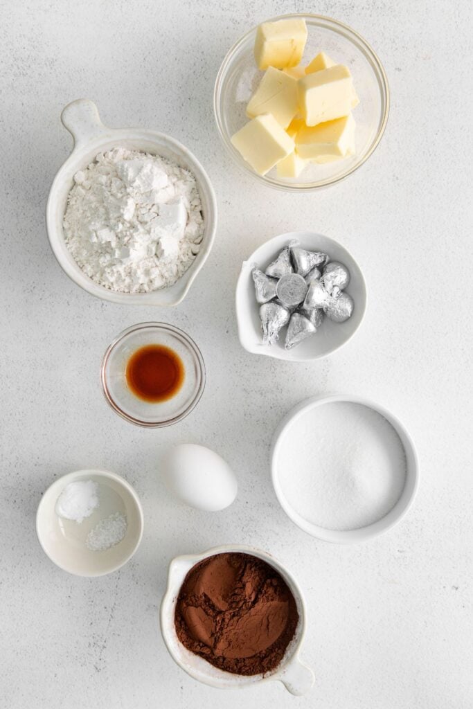 Ingredients needed to make chocolate kiss cookies: butter, sugar, egg, vanilla, flour, unsweetened cocoa powder, baking soda, salt, and Hershey kisses.