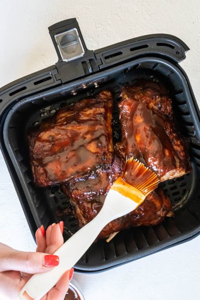 adding sauce to baby back ribs