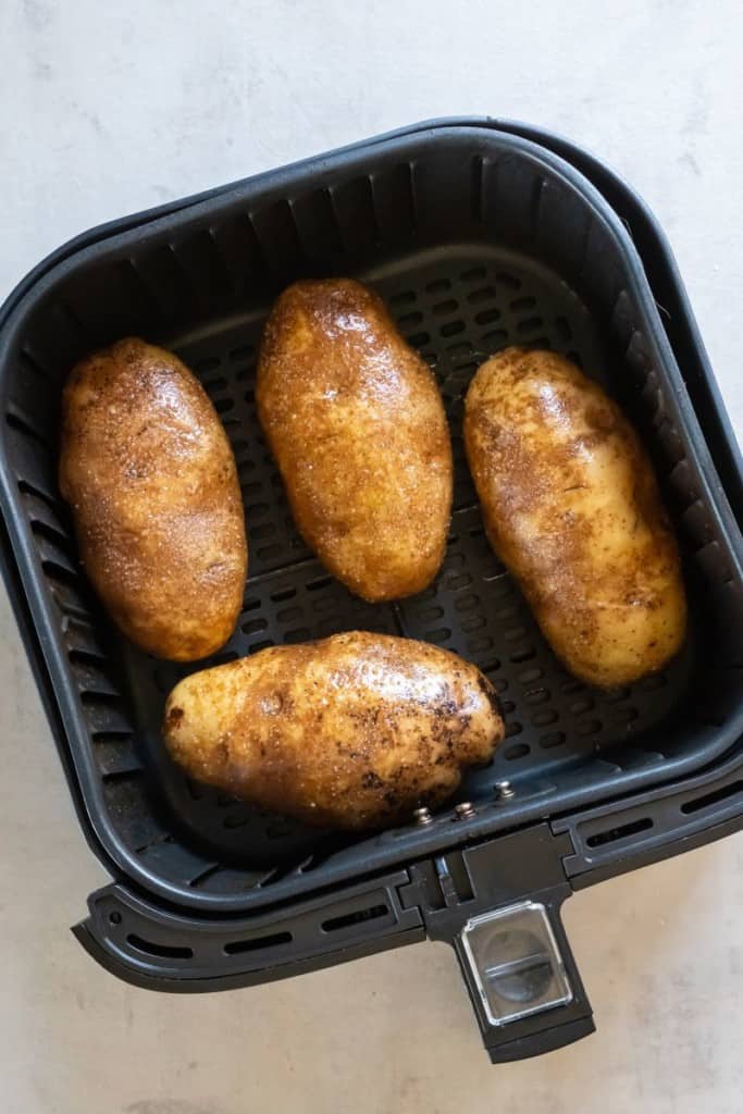 four potatoes in an air fryer basket