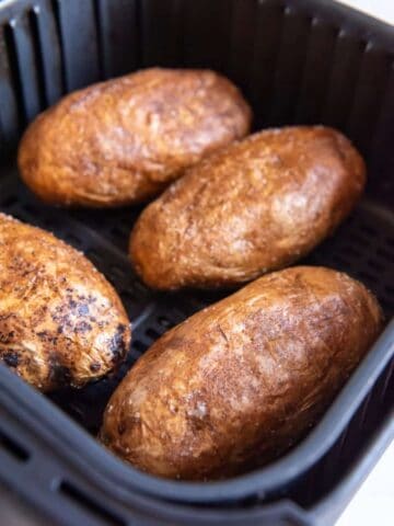 cooked baked potatoes in an air fryer basket