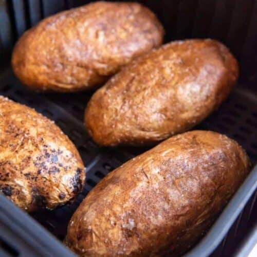 cooked baked potatoes in an air fryer basket