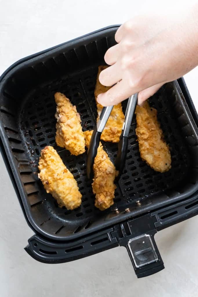 turning chicken tenders in an air fryer basket