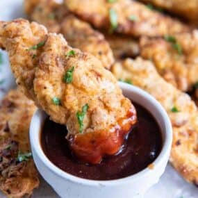 dipping chicken tender in barbecue sauce