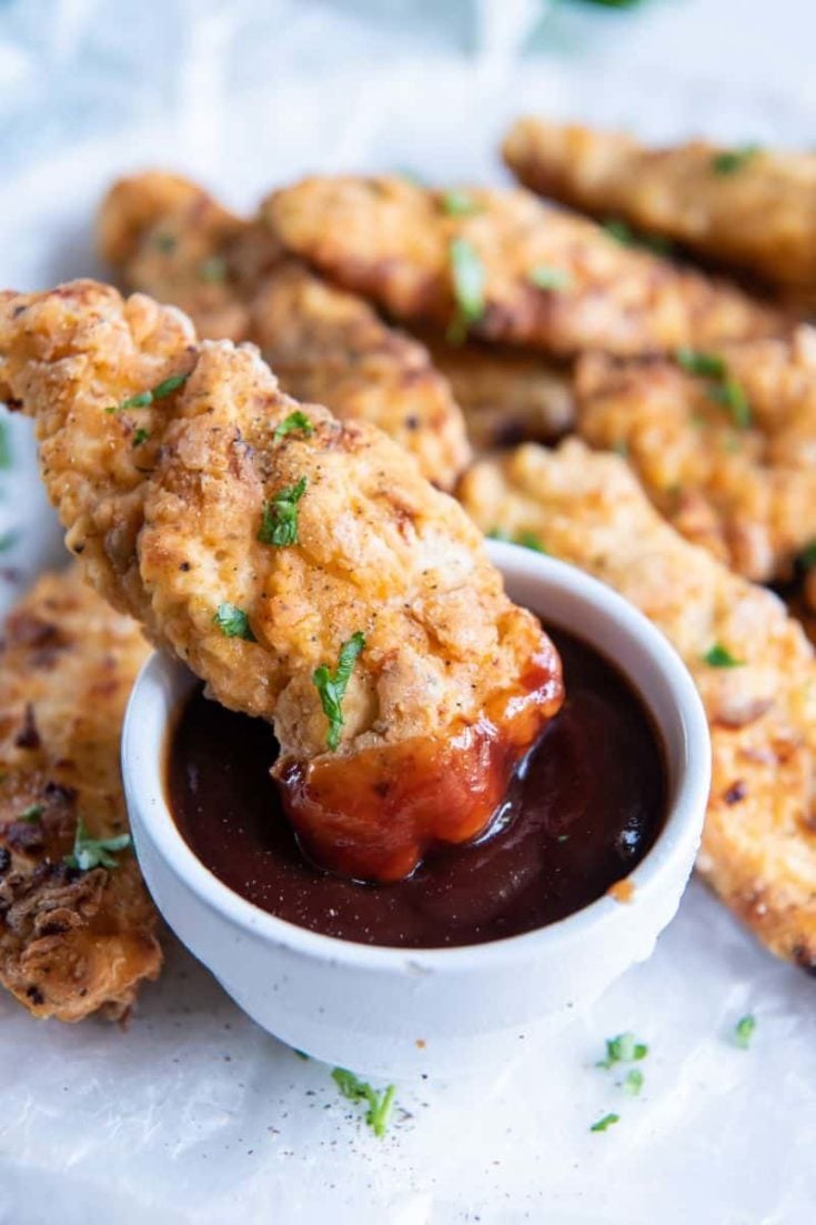 dipping chicken tender in barbecue sauce