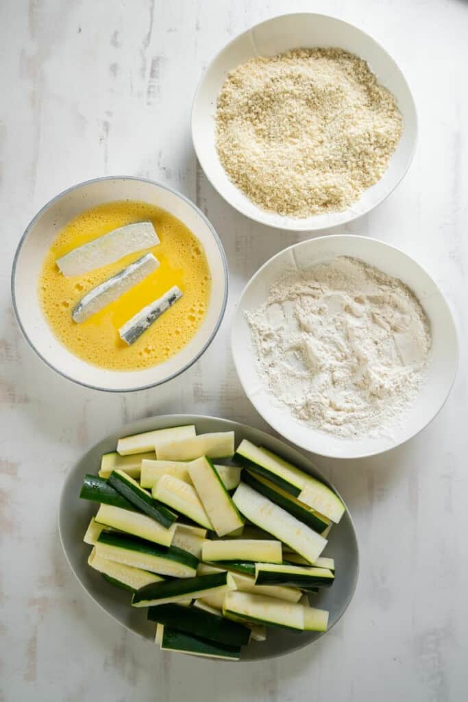 dipping zucchini fries into egg mixture