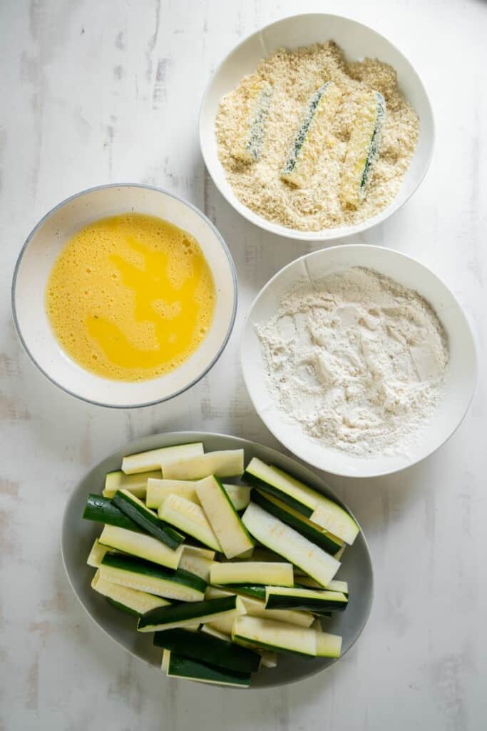 dipping zucchini fries into bread crumbs
