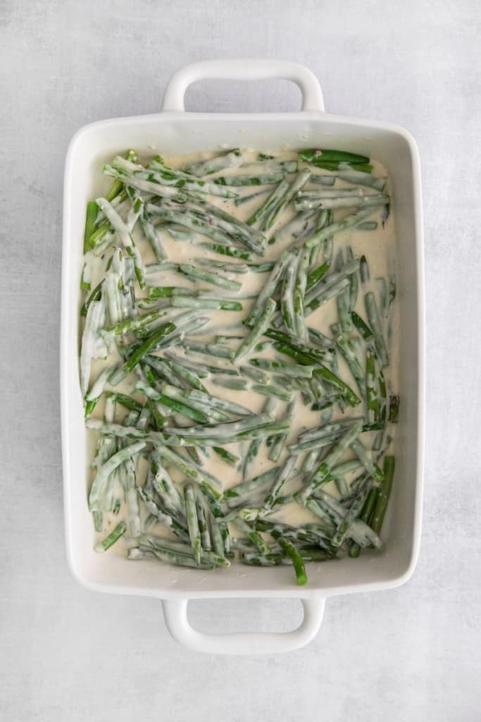 green beans in a casserole dish with sauce to make a homemade green bean casserole.