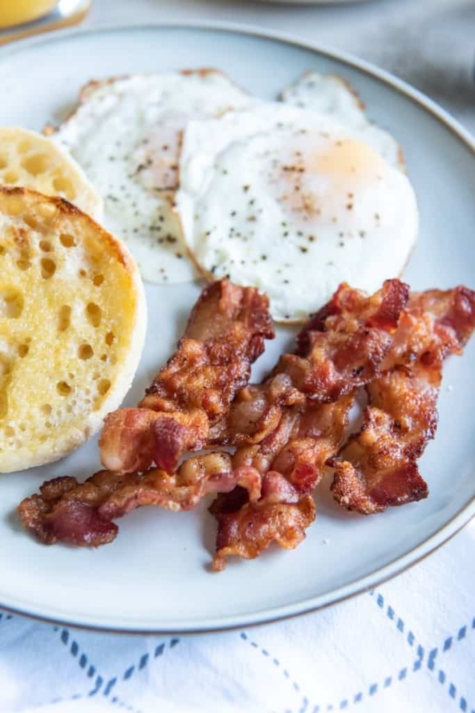 plate with bacon, eggs, and an english muffin