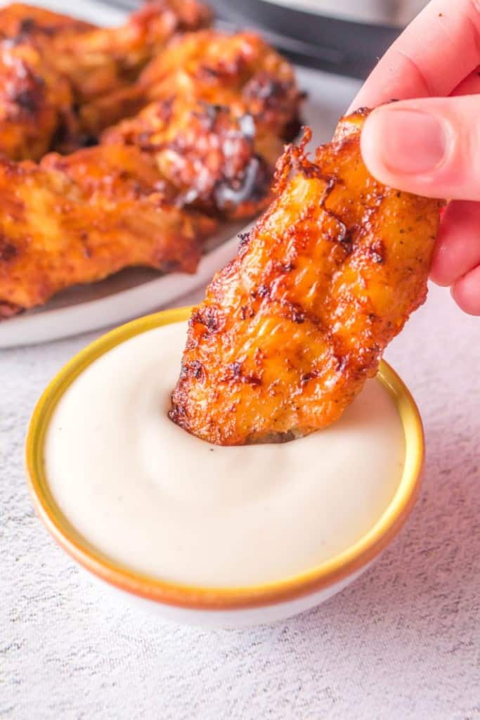 dipping chicken wing in sauce