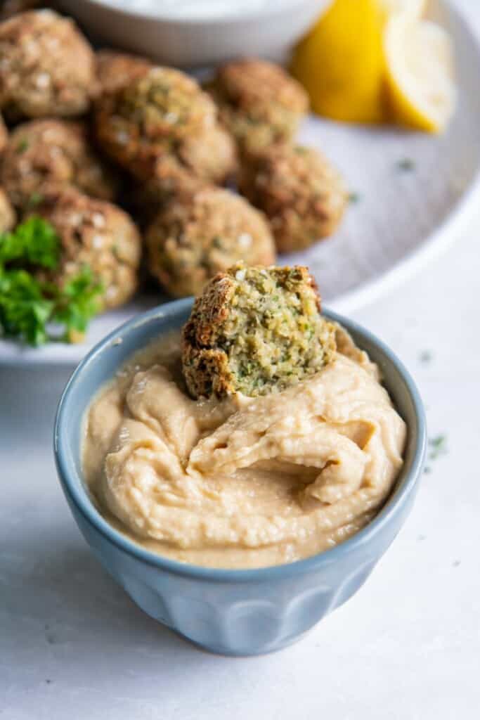 dipping falafel in a bowl with sauce