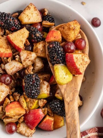 wooden spoon holding fall fruit salad