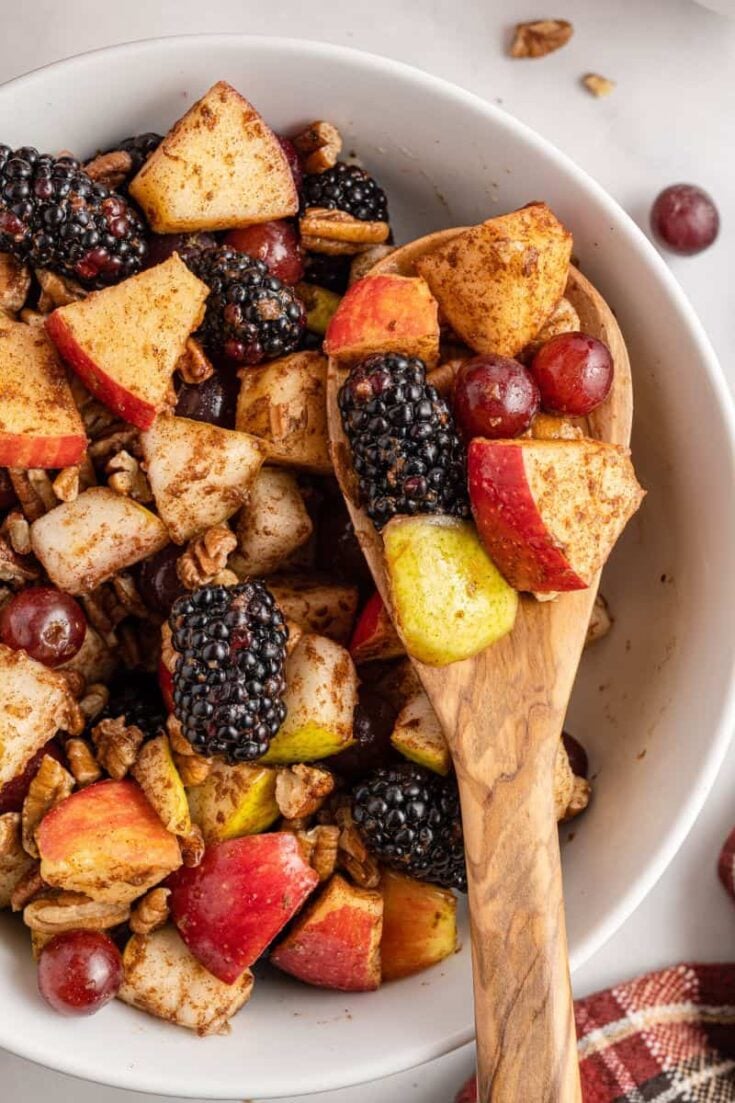 wooden spoon holding fall fruit salad