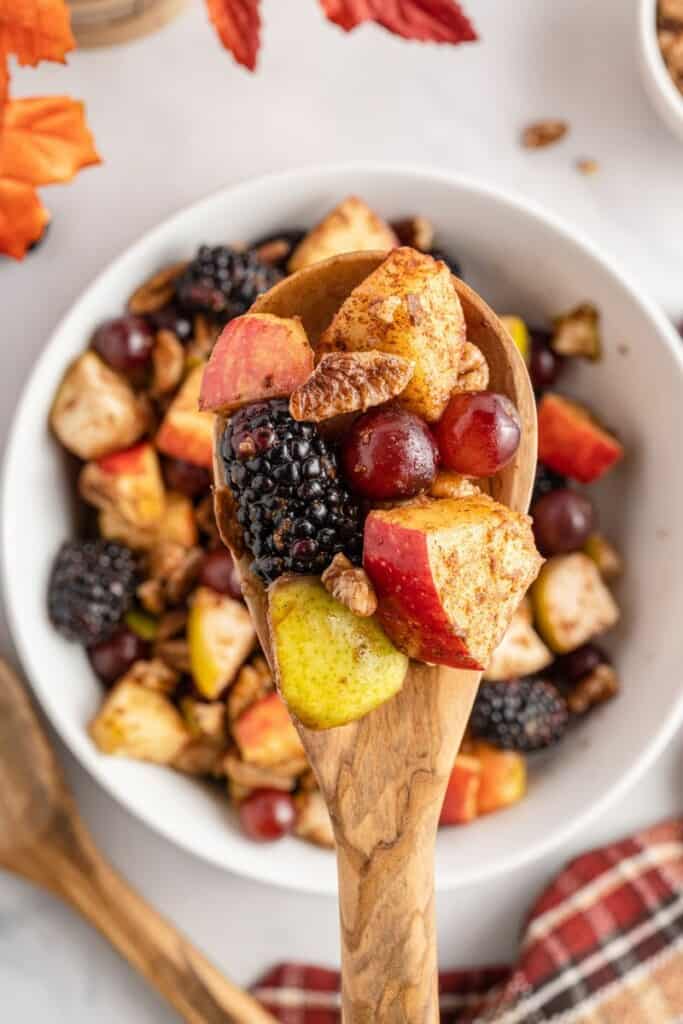 overhead shot of fall fruit salad on a wooden spoon