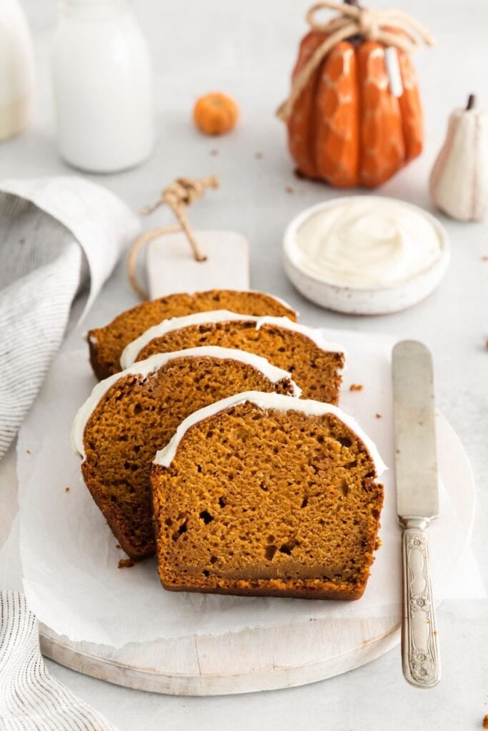 Pumpkin bread recipe on a plate sliced with a knife next to it.