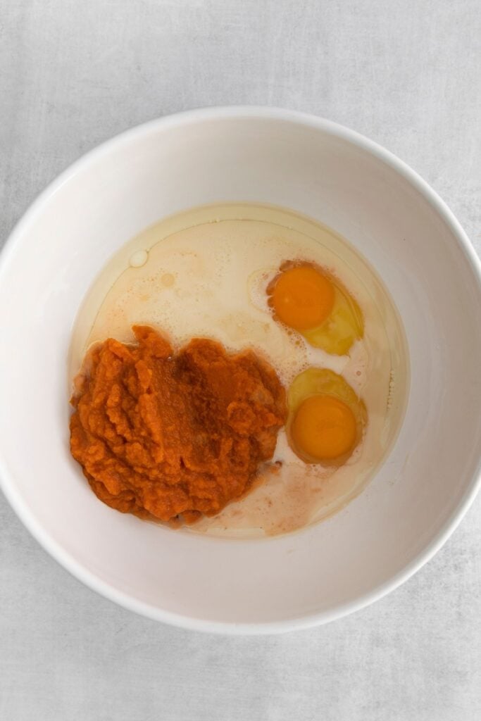 Wet ingredients in a white bowl (pumpkin puree, eggs, milk, and vanilla) ready to be mixed.