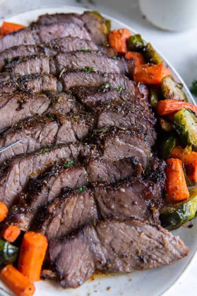 Air fryer chuck roast cut into slices and served with carrots and brussels sprouts.