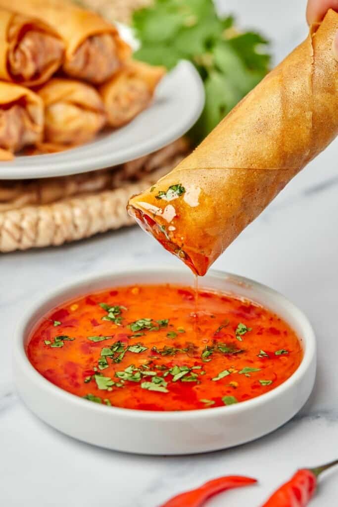 spring roll being dipped in sauce