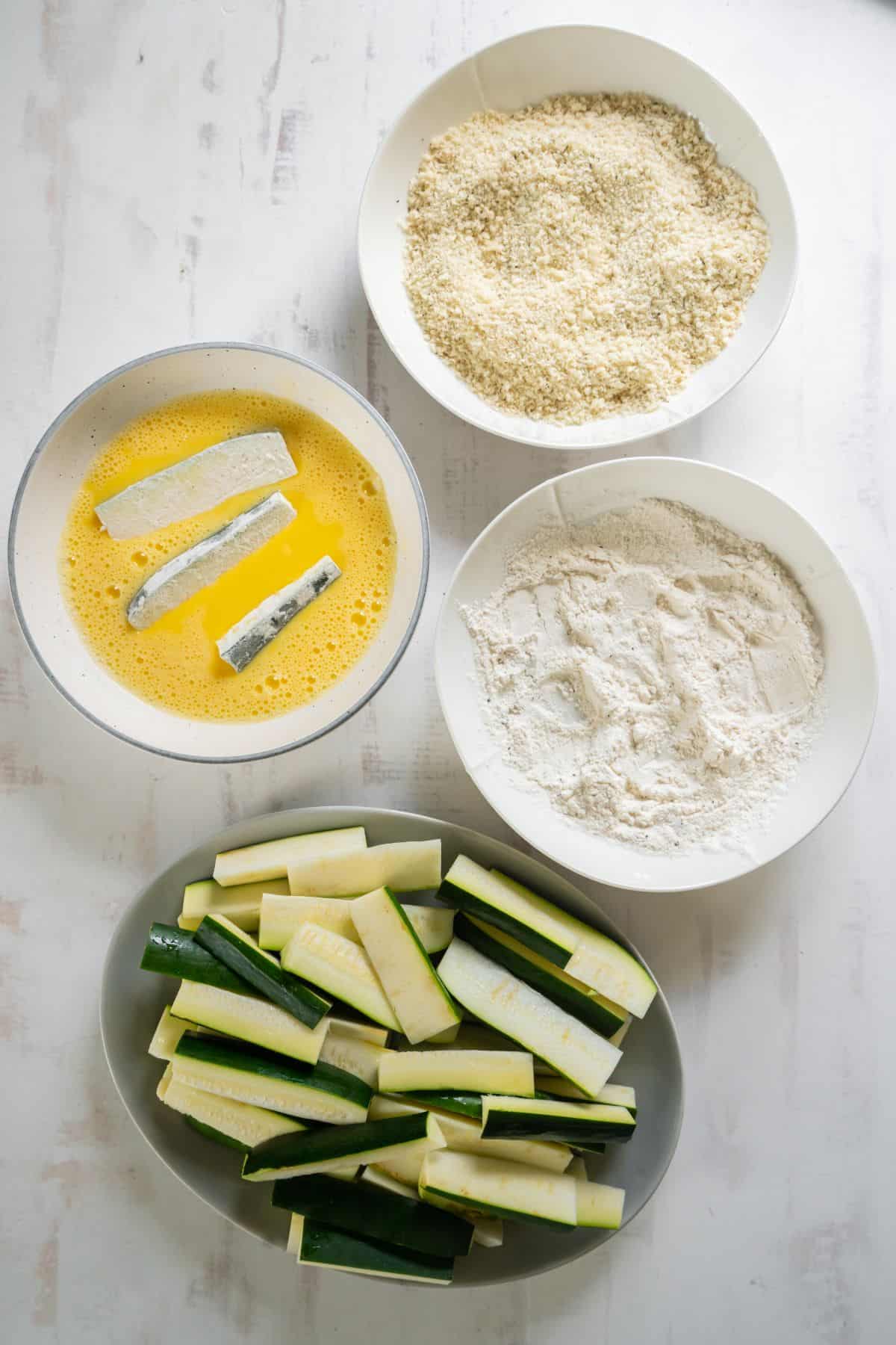 Zucchini fries being dipped into the egg.