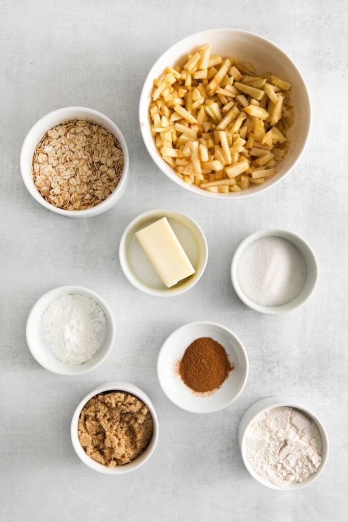 Ingredients needed to make the apple part of the apple cheesecake: apples, sugar, cornstarch, cinnamon, flour, brown sugar, rolled oats, and butter.