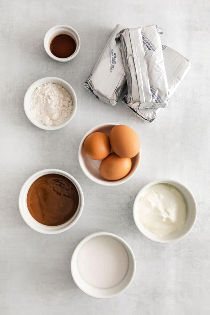 Ingredients needed to make the caramel cheesecake part: cream cheese, sugar, sour cream, caramel sauce, flour, vanilla, and eggs.