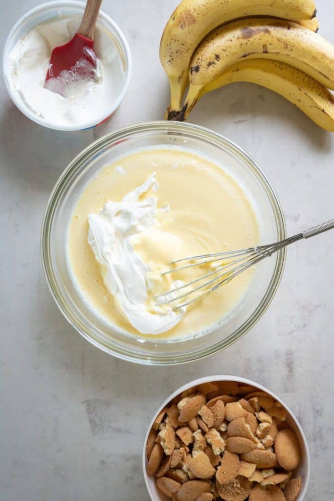 Cool Whip being folded into the banana pudding recipe with sour cream.