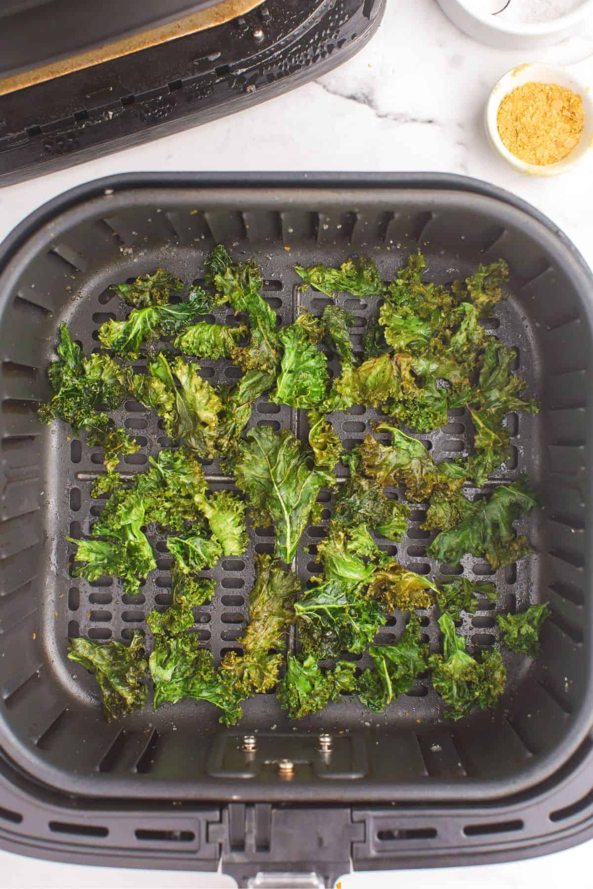 Cooked crispy kale chips in the air fryer basket.