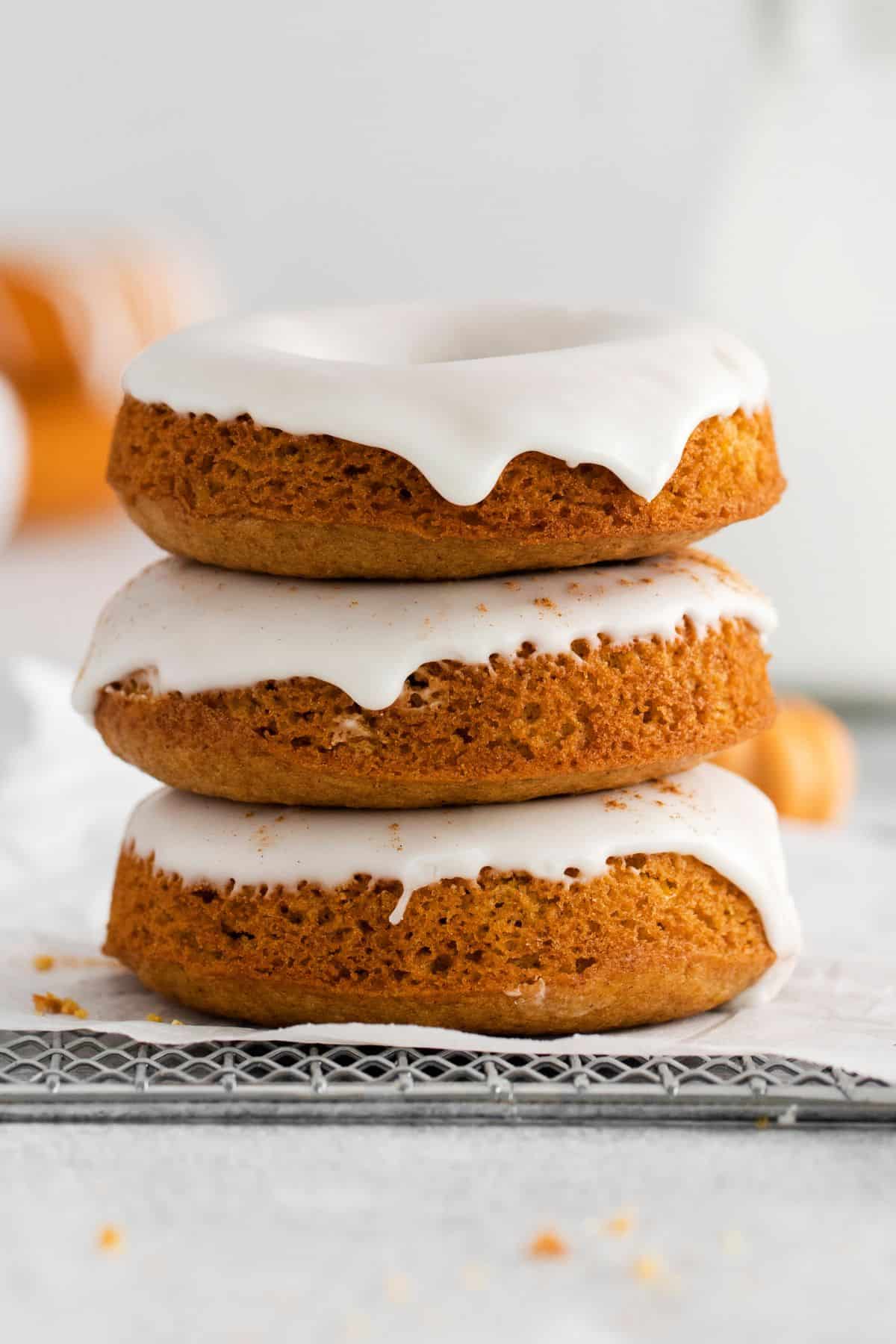 Pumpkin spice donuts topped with icing stacked on top of each other.