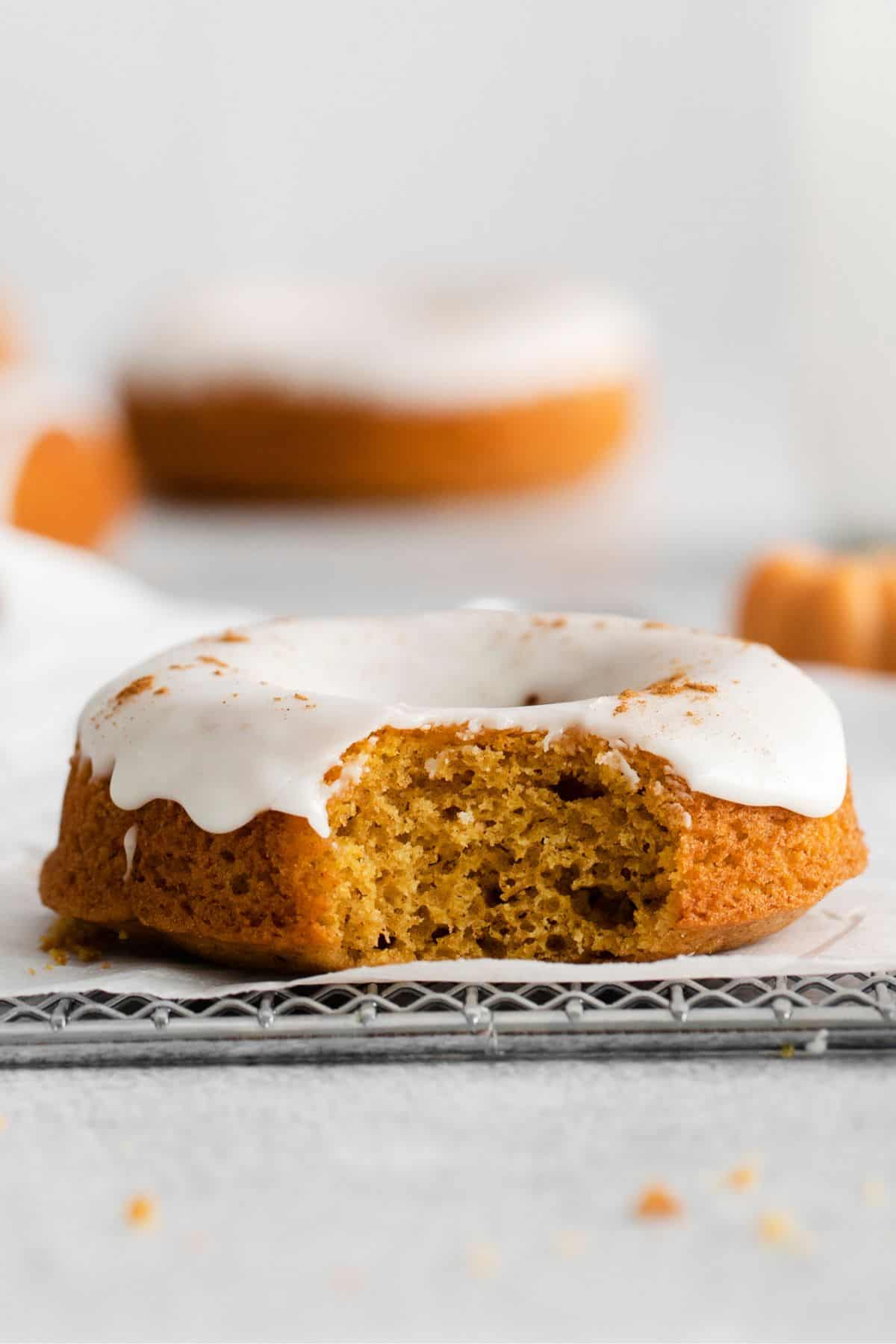 The pumpkin donut iced with a bite taken out of it to see the fluffy texture.