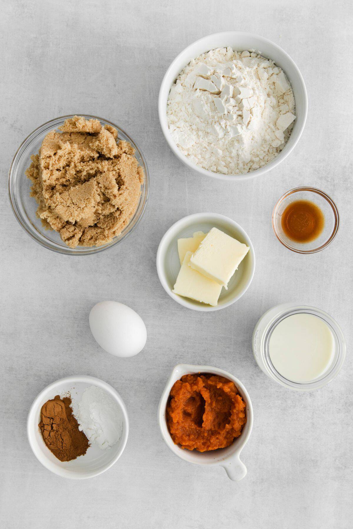 Ingredients needed to make pumpkin spice donuts: milk, pumpkin puree, butter, eggs, vanilla, flour, brown sugar, baking powder, pumpkin pie spice, and powdered sugar.