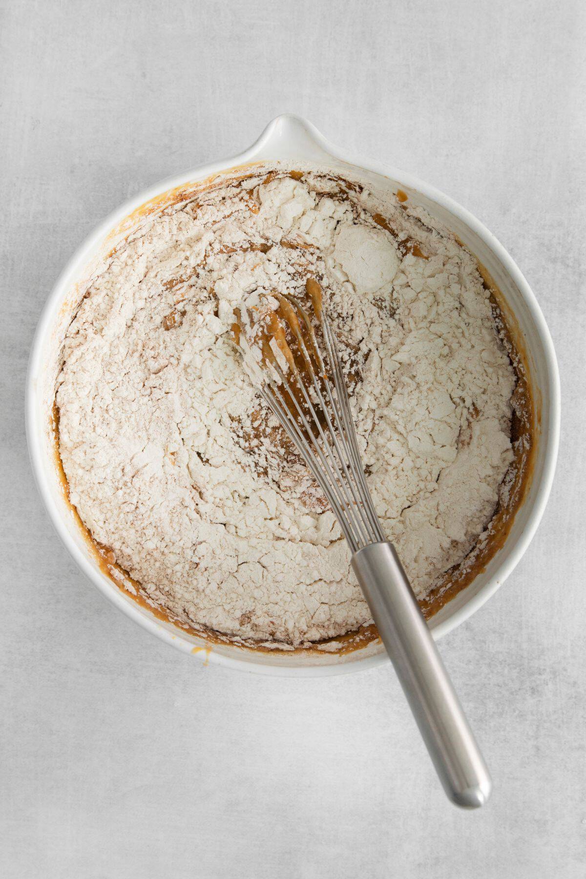 Flour being mixed into the batter with a whisk.