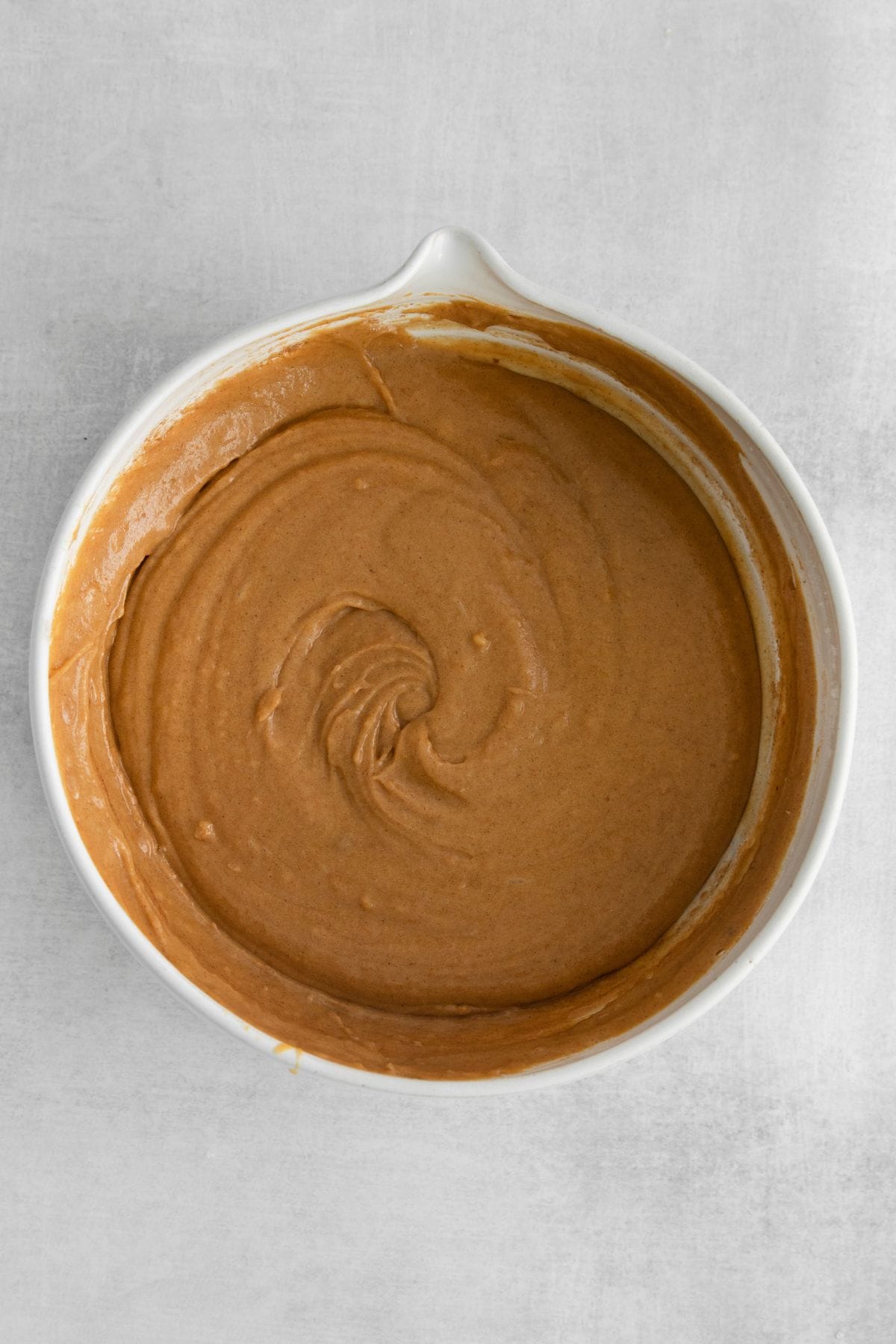 Pumpkin donut batter all ready to be scooped out, in a mixing bowl.