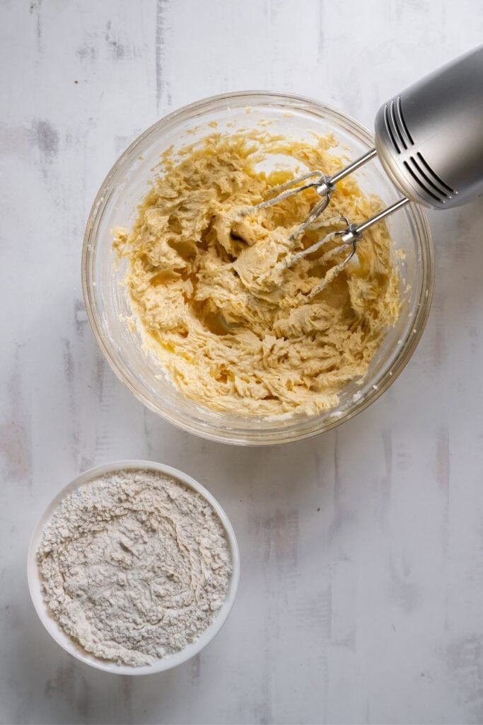 Batter for sugar cookies without baking soda in a mixing bowl with a hand mixer in it.