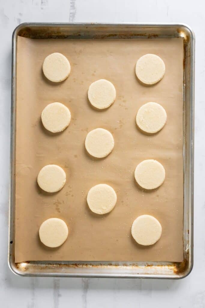 Pressed sugar cookies with no baking soda on a baking sheet on parchment paper ready to be baked.