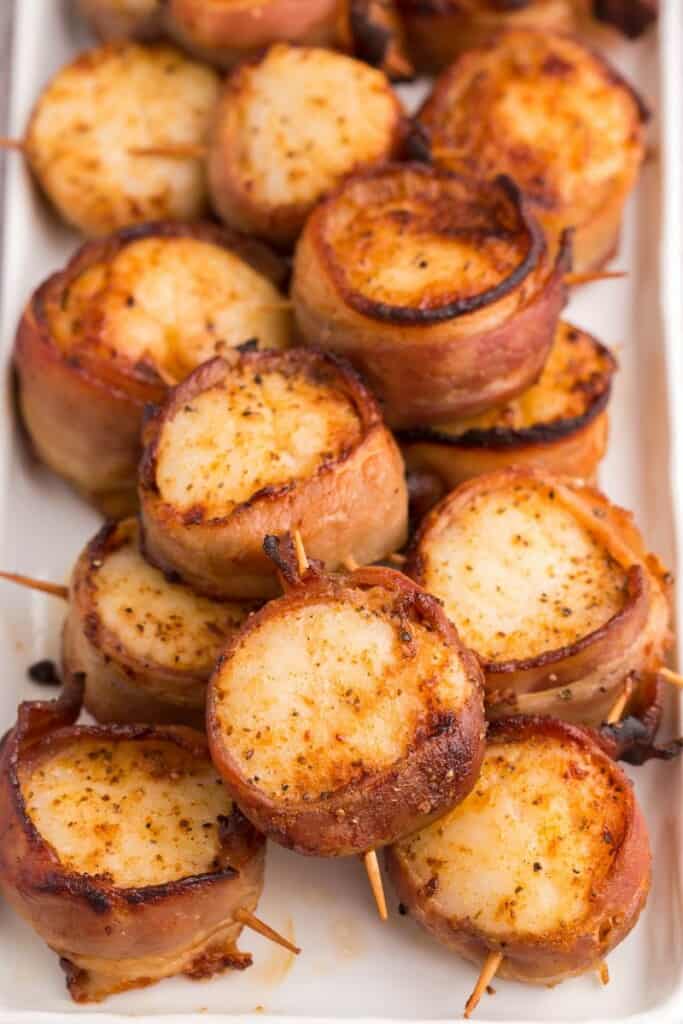 bacon wrapped scallops on a white platter