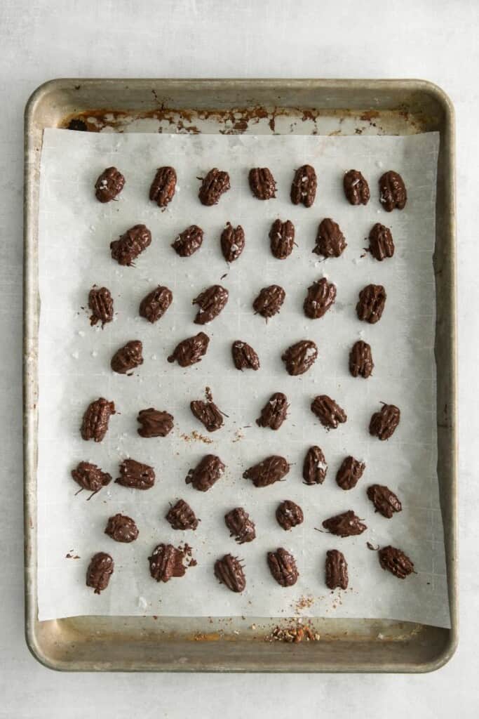 chocolate covered pecans on a baking sheet