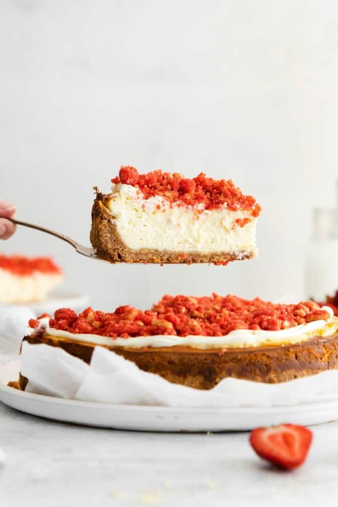 taking slice of strawberry crunch cheesecake out of pan