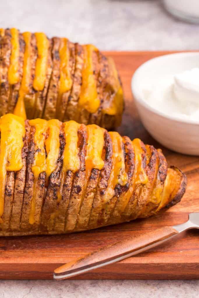 Close up of a hasselback potato on a cutting board.