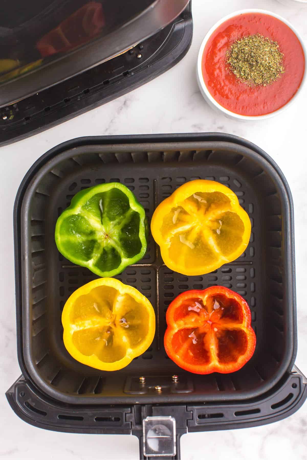 Stuffed bell peppers in an air fryer basket about to be air fried.
