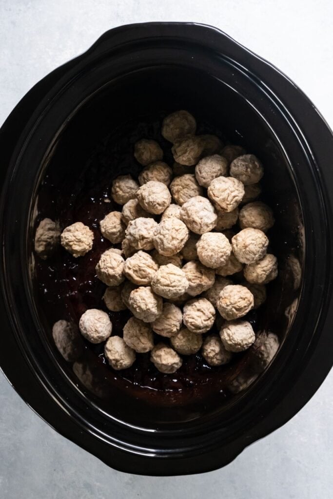 Frozen meatballs on top of the sauce in the crockpot to make BBQ grape jelly meatballs.