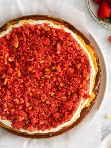 Finished strawberry cheesecake crunch cake recipe that's topped with the frosting and then the crunch topping.