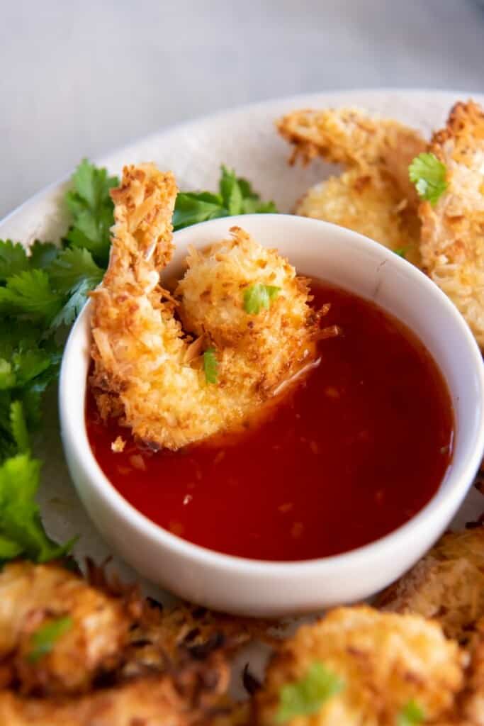 air fryer coconut shrimp being dipped in sauce